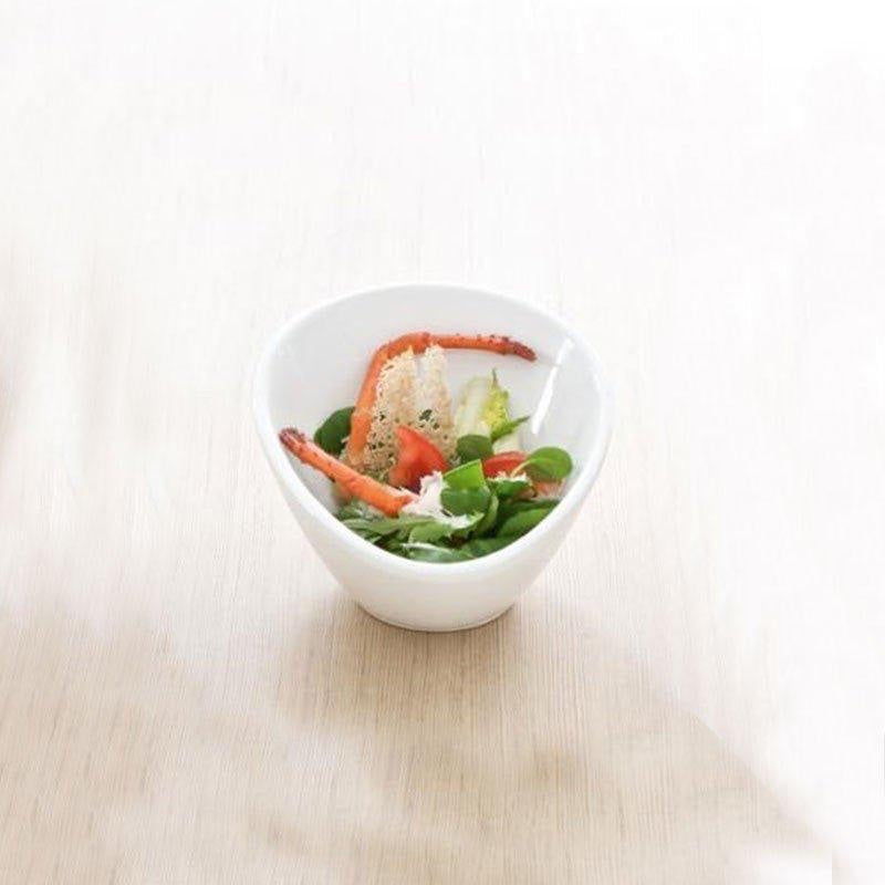 Eclectic ASA Selection Grande asymmetric white porcelain bowl filled with a fresh salad on a light wooden surface.