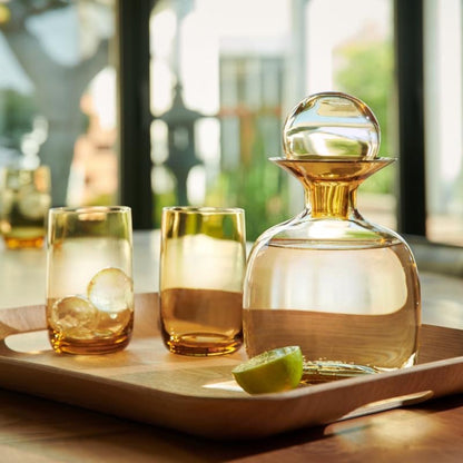 Eclectic ASA Selection Sarabi amber mouth-blown glass carafe and matching tumblers on a wooden serving tray.