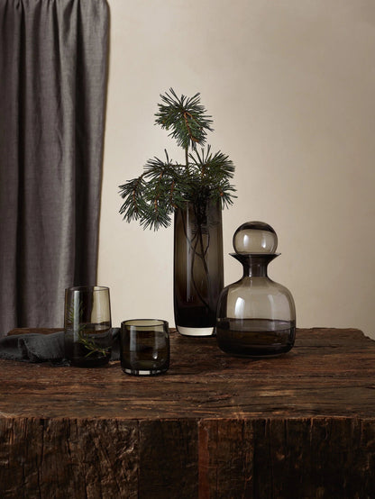 Eclectic ASA Selection Ajana smoky grey mouth-blown glass vase with a tall cylindrical shape on a rustic wooden table