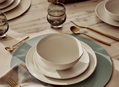 Eclectic ASA Selection spearmint vegan leather placemat under a white ceramic bowl and plate setting on a table.