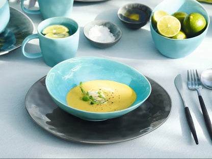Eclectic ASA Selection A La Plage turquoise crackle glaze oval stoneware bowl filled with soup on a dark dinner plate.