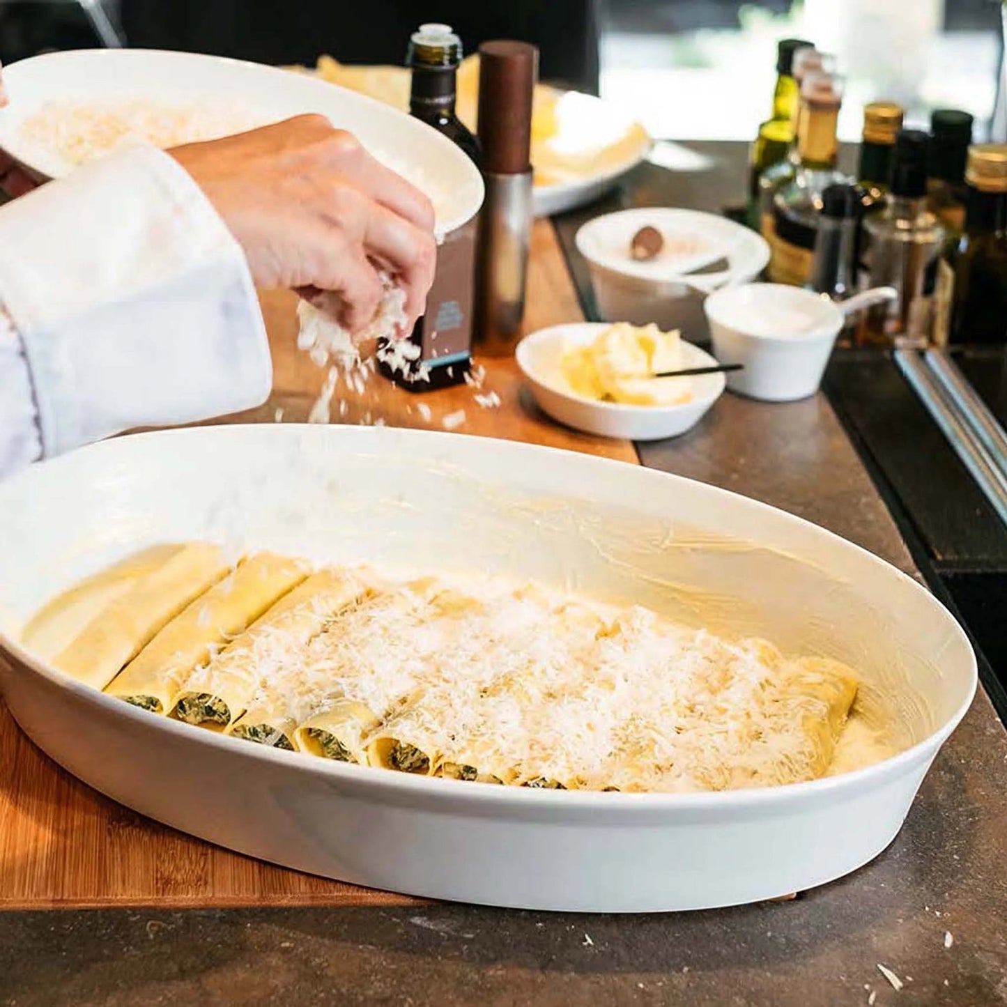Eclectic ASA Selection white porcelain oval roasting dish being filled with cannelloni in a professional kitchen
