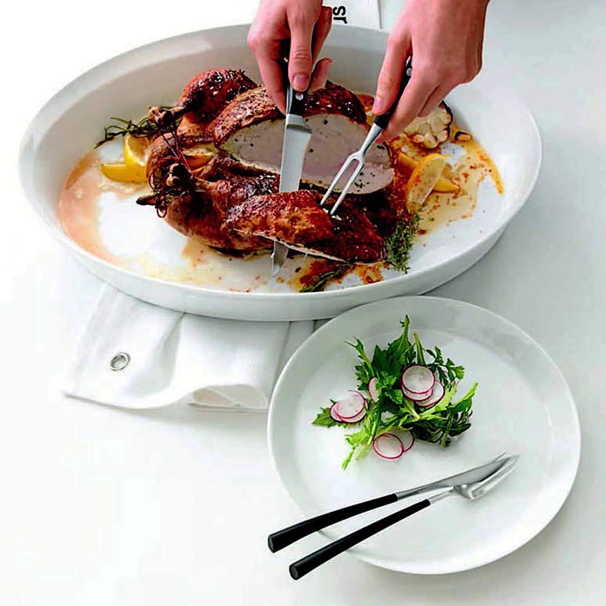 Eclectic ASA Selection white porcelain oval roasting dish containing a roasted chicken, served on a white table.