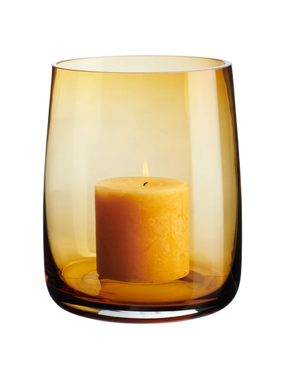 Eclectic ASA Selection Ajana amber mouth-blown glass vase and candle holder with a pillar candle on a black background