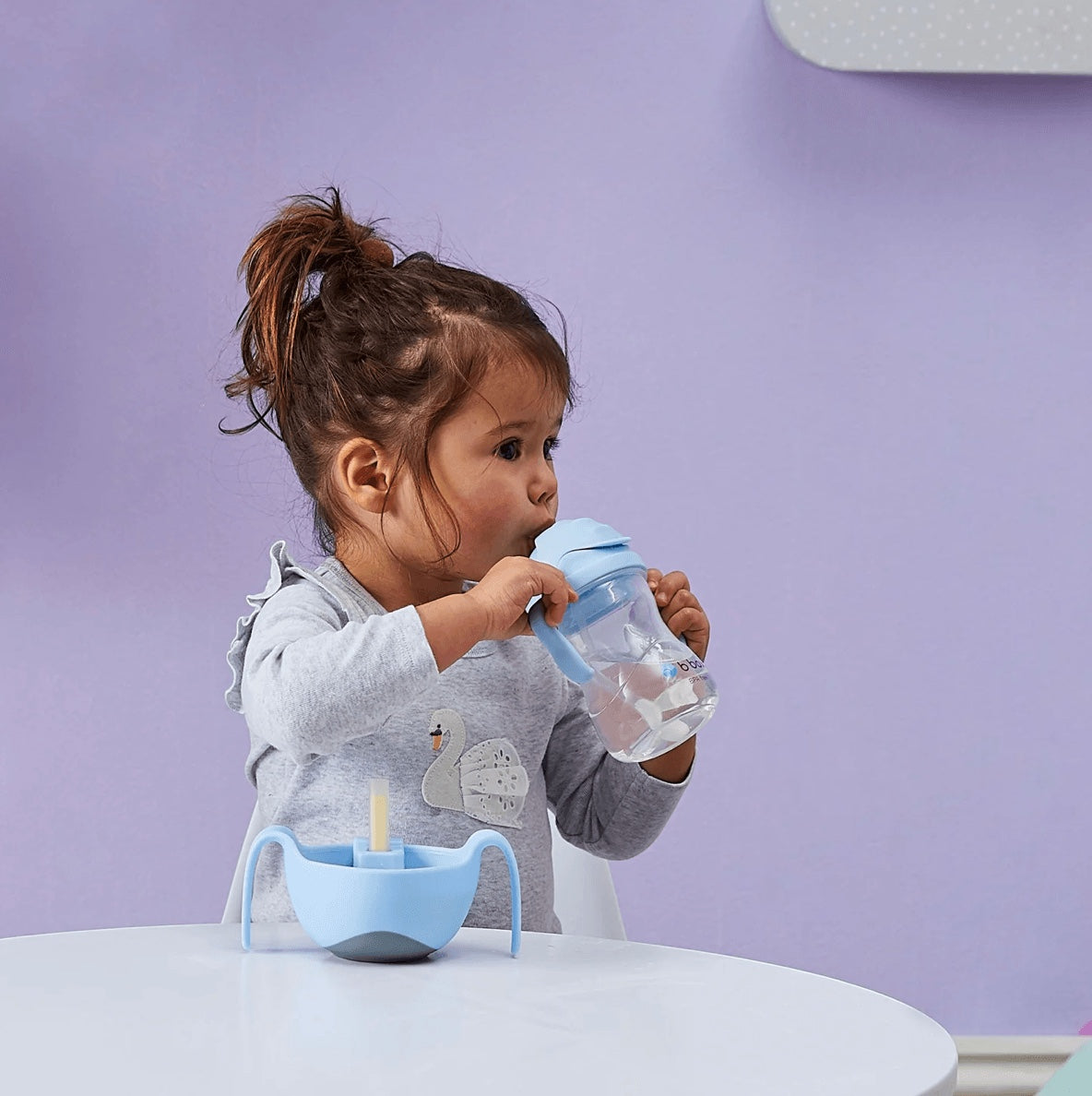Eclectic b.box bubblegum sippy cup with weighted straw held by a toddler at a table