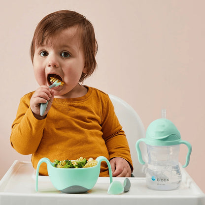 Eclectic b.box pistachio sippy cup and bowl set with a toddler eating in a high chair