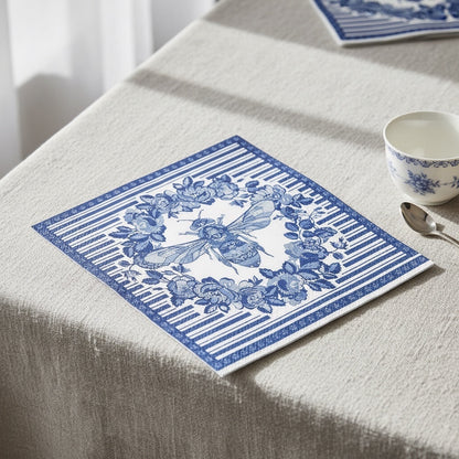 Eclectic Bee Blue disposable napkins with botanical bee motif on a linen-textured table setting.