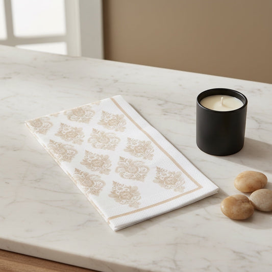 Eclectic beige damask airlaid napkin with linen-like texture on a marble table next to a black candle.