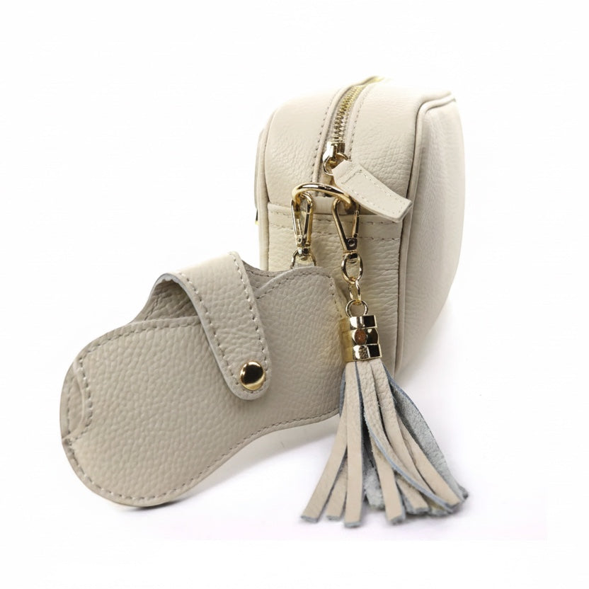 Eclectic leather glasses case in beige with gold-tone snap button and clip, attached to a matching leather bag.