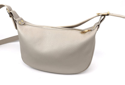 Eclectic beige grained leather half moon sling bag with gold-tone hardware and an adjustable crossbody strap.