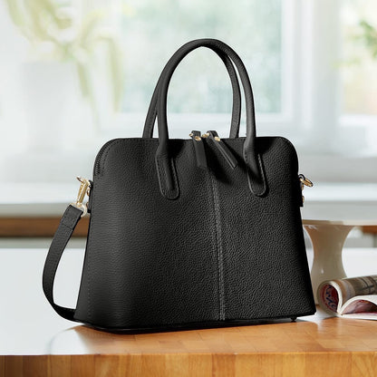 Eclectic Bella structured black Italian leather handbag with silver hardware and top handles on a wooden table.