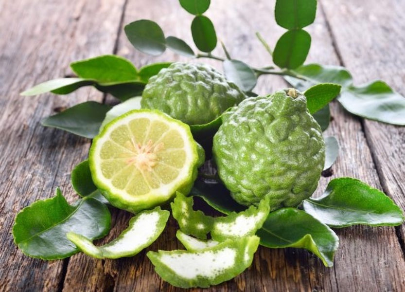 Eclectic La Provence bergamot and lemon citrus fruit with green leaves on a rustic wooden surface