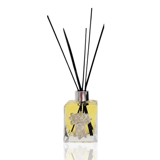 Eclectic Bergamot & Lemon reed diffuser in a square glass bottle with a pewter-style emblem and black reeds.