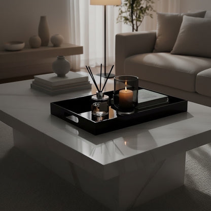 Eclectic black acrylic serving tray with a mirrored base styled with a candle and diffuser on a white coffee table