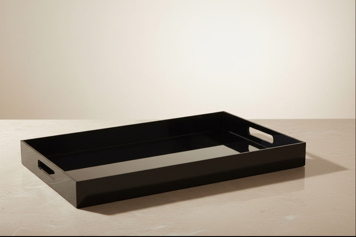 Eclectic black acrylic serving tray with integrated handles on a neutral surface for modern home decor styling.