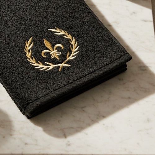 Eclectic black cotton guest towel featuring a luxurious gold embroidered crown and laurel wreath design.