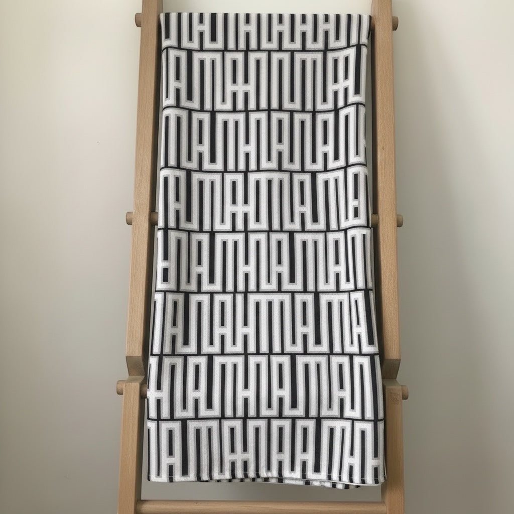 Eclectic black and white geometric patterned tablecloth with a soft linen-look finish draped over a wooden ladder.