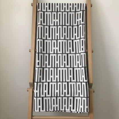 Eclectic black and white geometric patterned tablecloth with a soft linen-look finish draped over a wooden ladder.