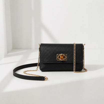 Eclectic black pebbled leather clutch with a bamboo-inspired gold clasp and detachable gold chain strap.