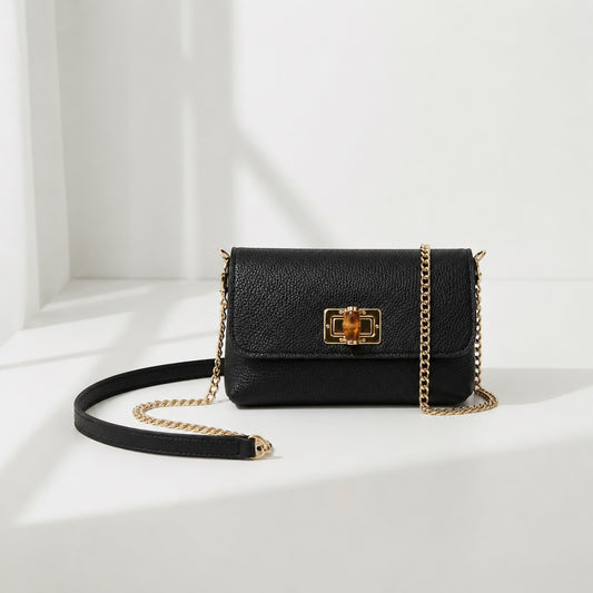 Eclectic black pebbled leather clutch with a bamboo-inspired gold clasp and detachable gold chain strap.