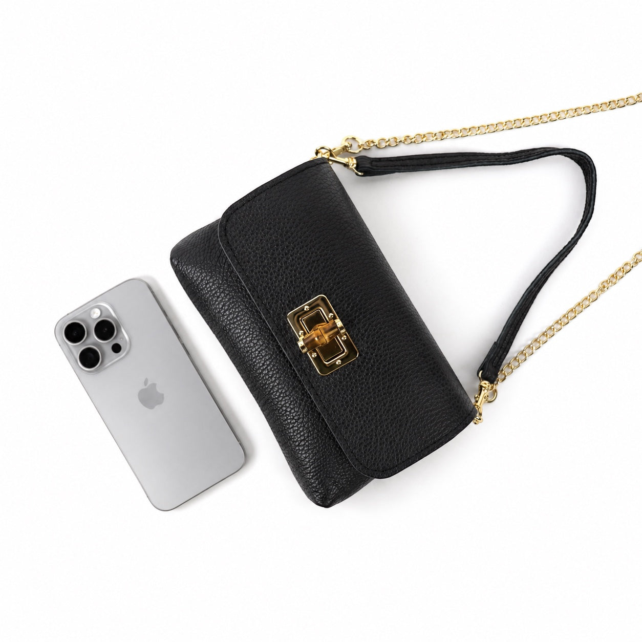 Eclectic black pebbled leather clutch with gold bamboo clasp and chain strap next to a smartphone on white background