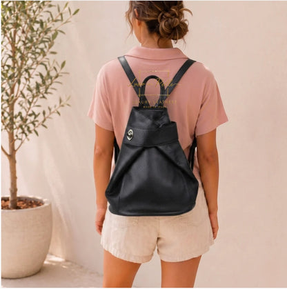 Eclectic black pebbled Italian leather fold-over backpack worn by a woman with adjustable shoulder straps