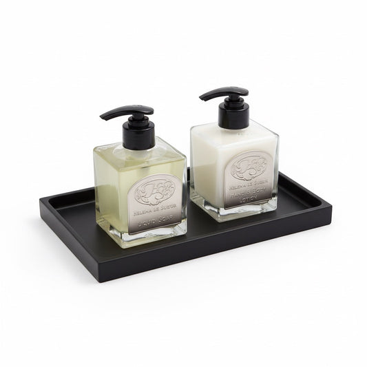 Eclectic minimalist black silicone vanity tray holding two glass soap and lotion dispensers on a white background