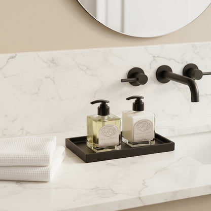 Eclectic minimalist black silicone vanity tray holding soap and lotion bottles on a marble bathroom counter.