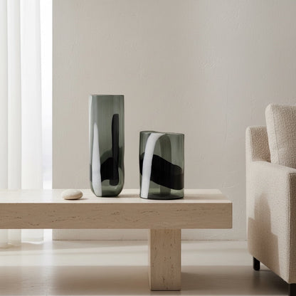 Eclectic black and white glass cylinder vases with abstract patterns displayed on a modern travertine coffee table.