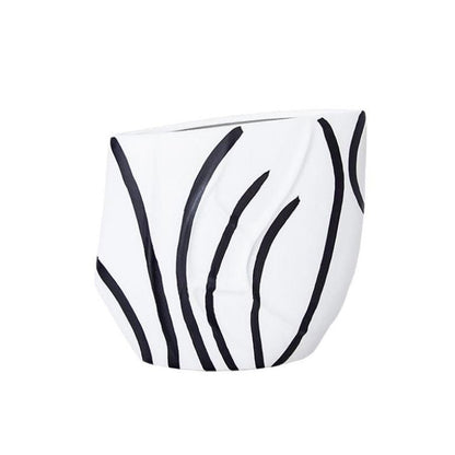 Eclectic black and white ceramic vase with a curved silhouette and graphic reed-inspired pattern in a gloss finish.