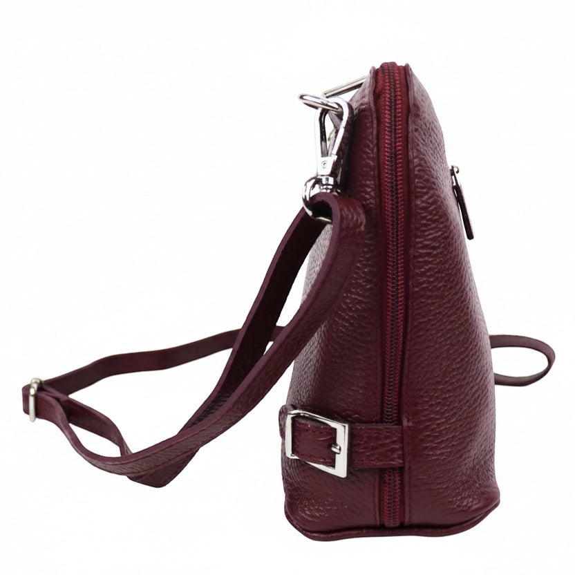 Eclectic burgundy grained leather crossbody bag with side buckle detail and silver hardware, side view.