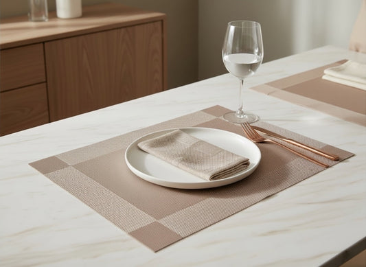 Eclectic champagne woven PVC rectangular placemat with a subtle sheen on a white marble dining table
