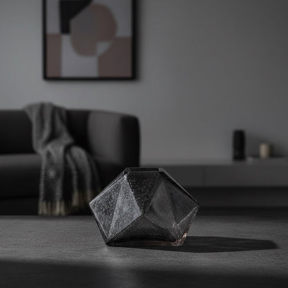 Eclectic charcoal diamond glass vase with a faceted geometric design on a dark surface in a modern living room.