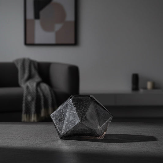 Eclectic charcoal diamond glass vase with a faceted geometric design on a dark surface in a modern living room.
