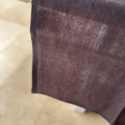 Eclectic charcoal 100% linen table runner with stitched edges draped over a surface