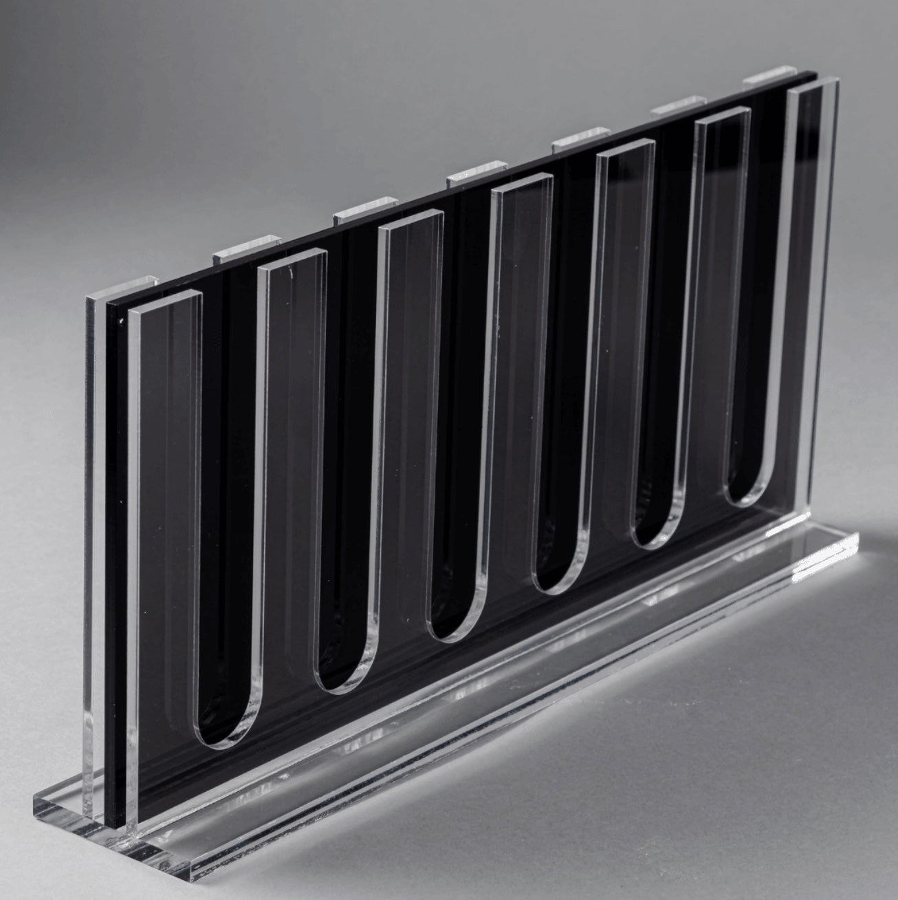Eclectic clear acrylic espresso pod stand with a slim, double-sided design for 60 coffee capsules on a grey background.