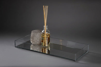 Eclectic clear acrylic mirrored display tray holding a glass reed diffuser and a textured decorative candle holder.