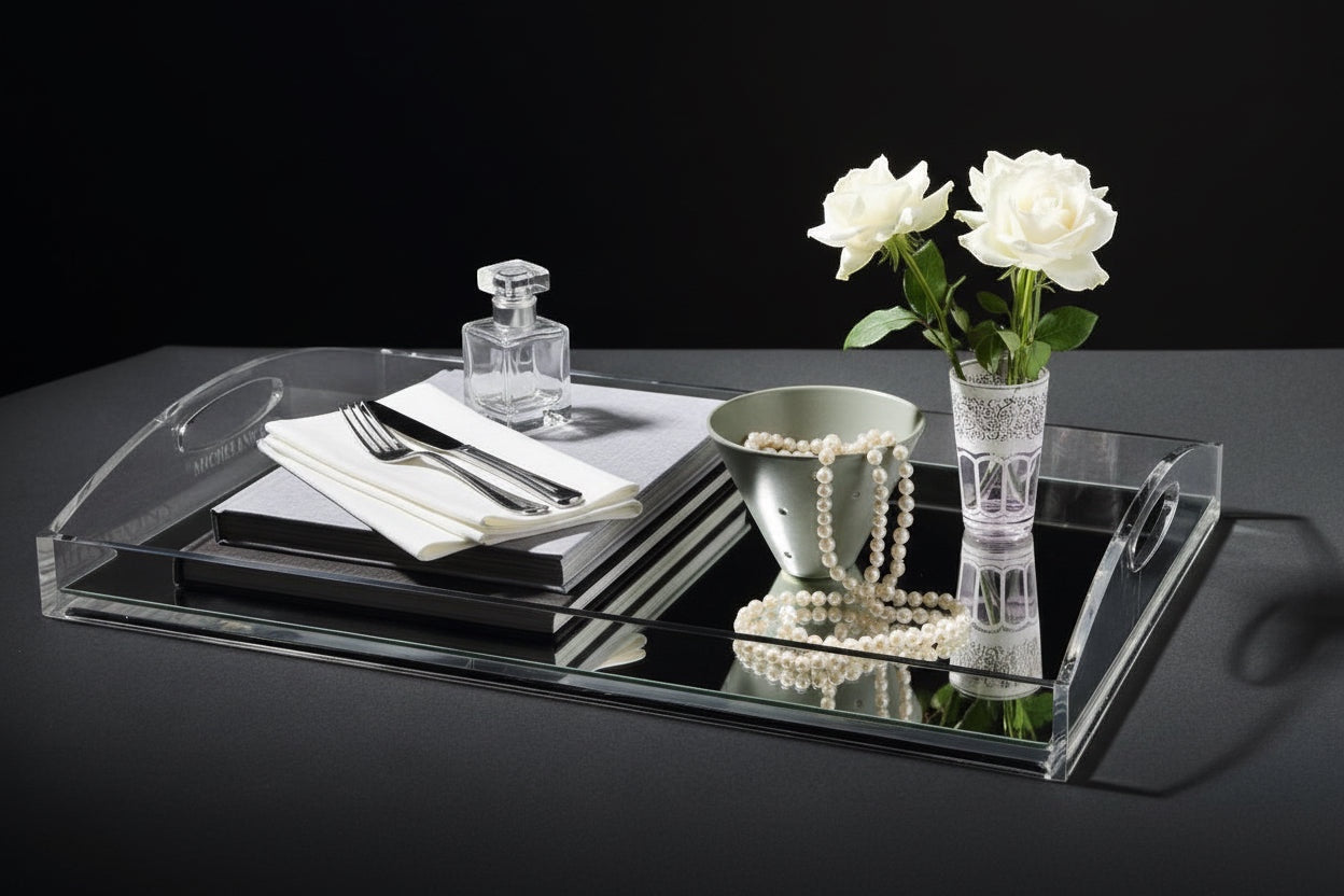 Eclectic clear acrylic gallery tray with a mirrored base styled with white roses, pearls, and books on a table.