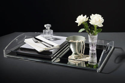 Eclectic clear acrylic gallery tray with a mirrored base styled with white roses, pearls, and books on a table.