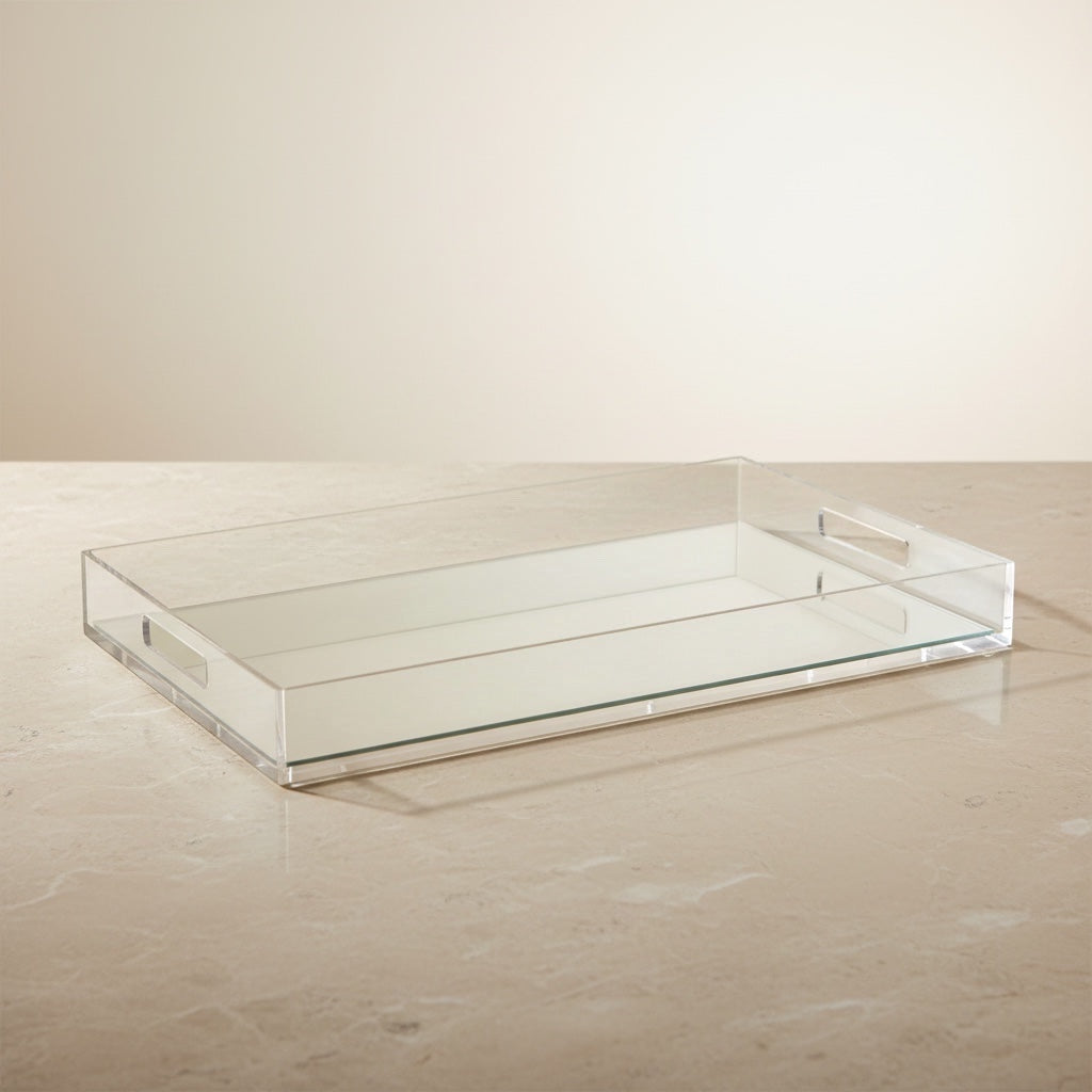 Eclectic clear acrylic mirrored serving tray with integrated handles sitting on a neutral stone surface