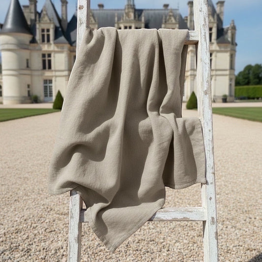 Eclectic Daiva Lino natural stone linen cotton blend tablecloth draped over a rustic wooden ladder outdoors
