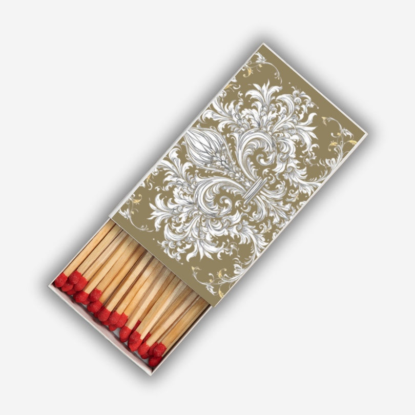 Eclectic decorative matchbox featuring ornate white floral damask pattern on a gold background with long red-tipped matches.
