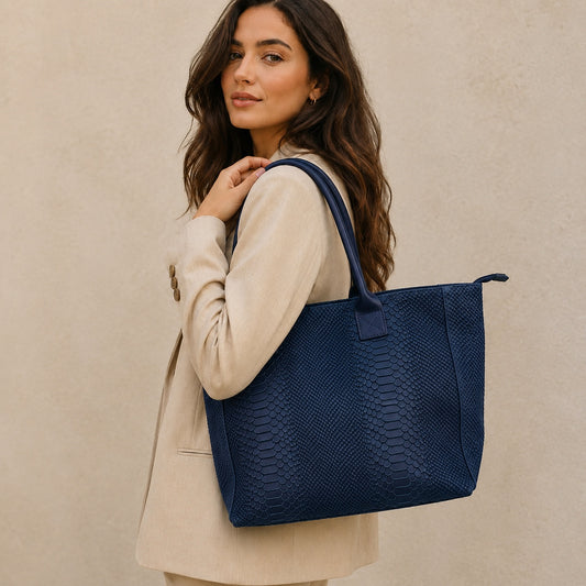 Eclectic Florenza denim blue snake-print suede shopper bag worn over the shoulder by a woman in a beige blazer