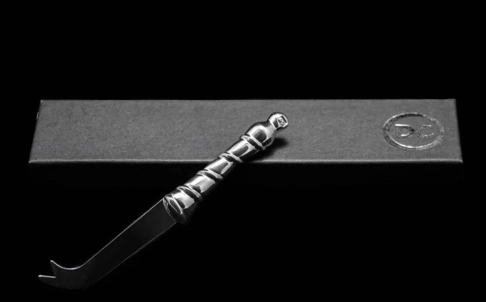 Eclectic Diana Carmichael Ribbon pewter cheese knife with a sculptural vine-inspired handle on a black gift box.
