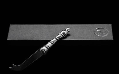 Eclectic Diana Carmichael Ribbon pewter cheese knife with a sculptural vine-inspired handle on a black gift box.