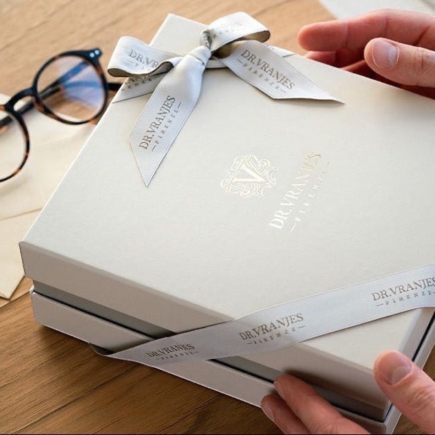 Eclectic Dr. Vranjes Ambra gift set in an elegant cream box with branded ribbon held by hands on a wooden desk