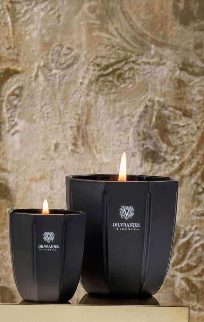 Eclectic Dr. Vranjes Ambra scented candles in black onyx glass vases with burning wicks against a textured wall.