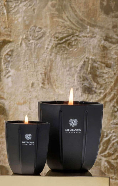 Eclectic Dr. Vranjes Ambra scented candles in black onyx glass vases with burning wicks against a textured wall.