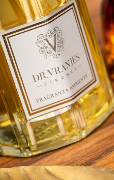 Eclectic Dr Vranjes Ambra reed diffuser featuring a glass bottle with a gold-bordered label and natural rattan sticks.
