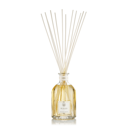 Eclectic Dr Vranjes Ambra reed diffuser in a classic glass bottle with natural rattan sticks against a black background